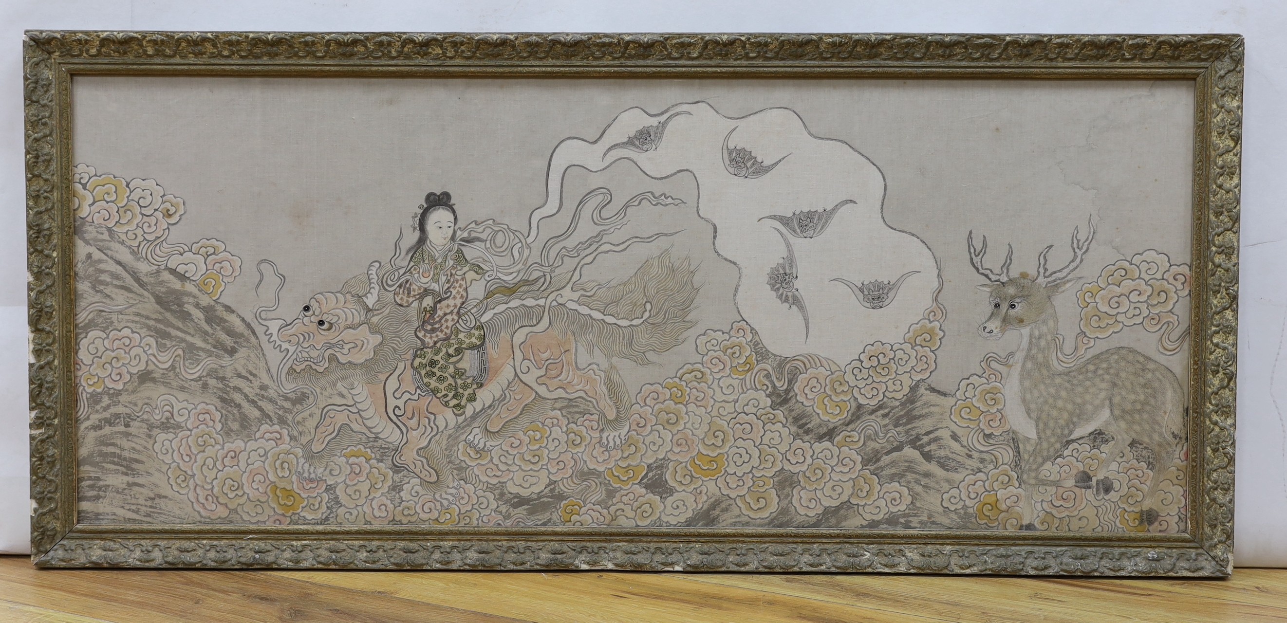 A framed Chinese silk study depicting a tranquil landscape of figure riding a dragon amongst foliage and other animals, 48 x 119cm